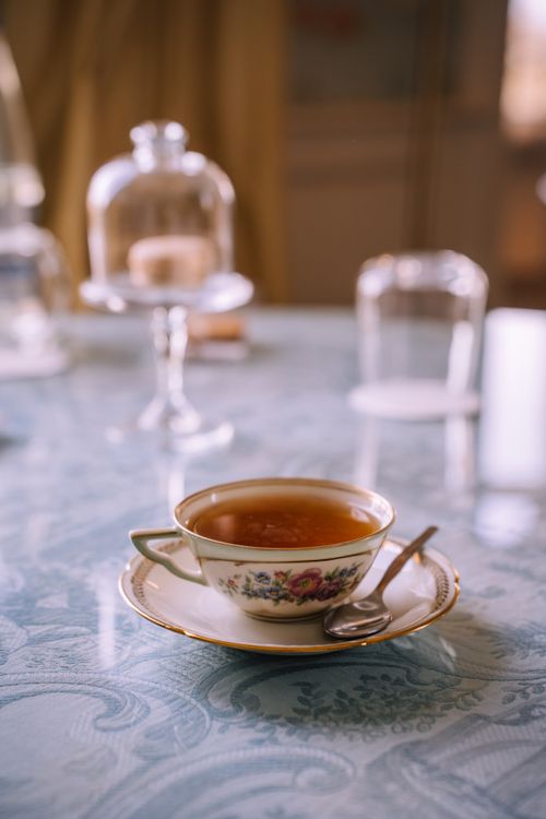 Free A vintage teacup filled with tea on a light blue patterned table, creating a cozy atmosphere. Stock Photo