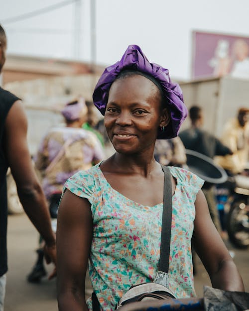A woman in a purple head wrap smiles for the camera