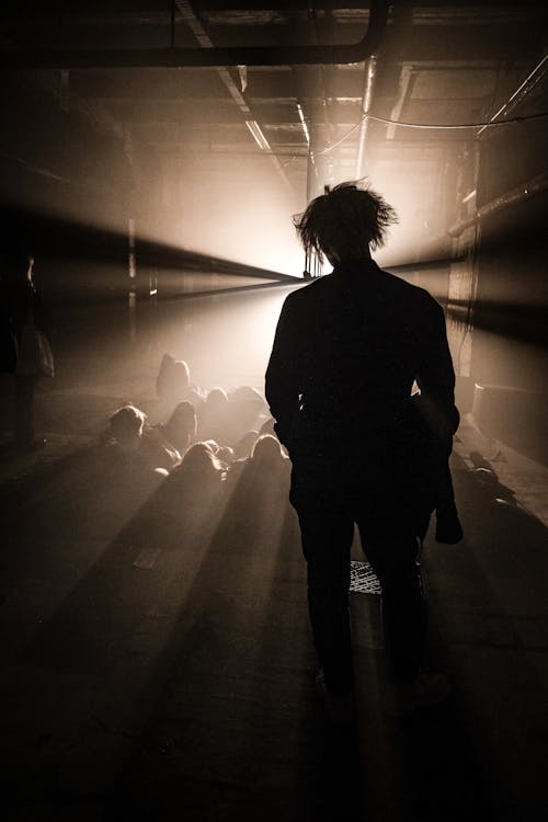 A man standing in a dark room with light coming from behind him