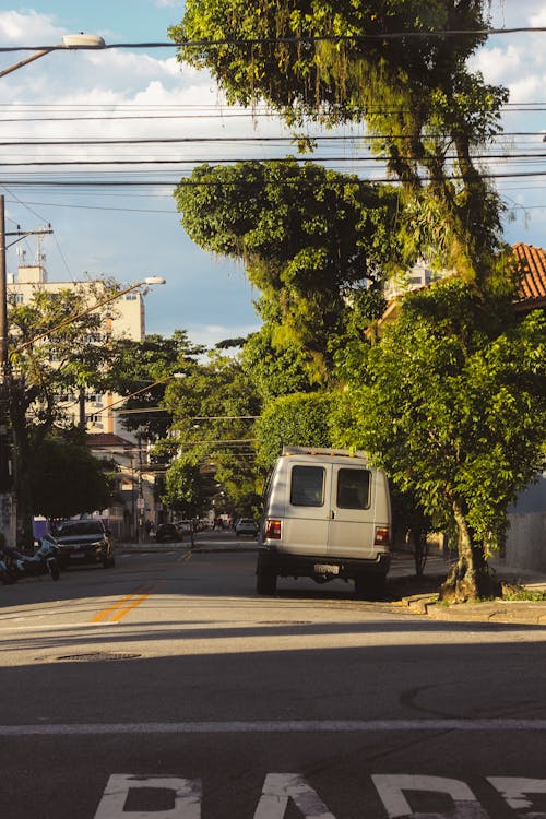 A van driving down a street with trees and a street sign