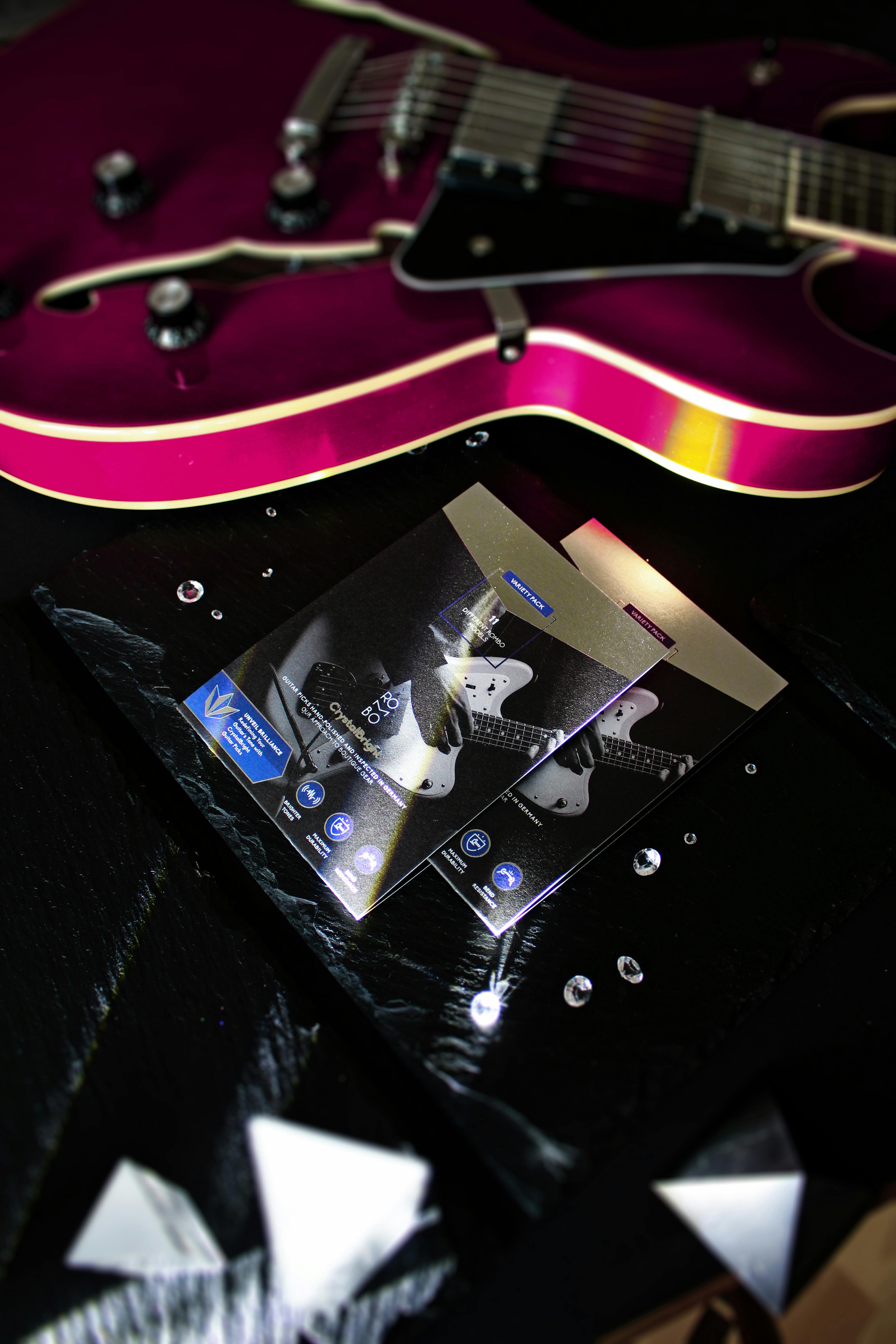 Detailed view of a pink electric guitar next to sheet music on a dark surface, ideal for music themes.