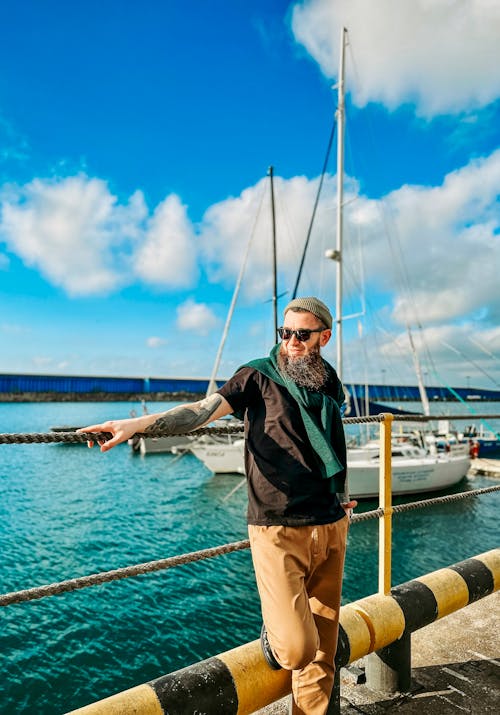 A man with a beard and a hat pointing at a boat