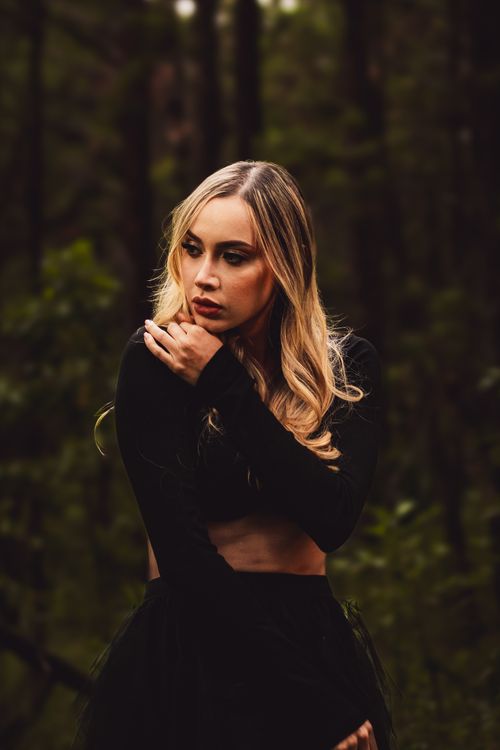 Free Moody portrait of a woman in a forest setting, showcasing deep fashion tones. Stock Photo