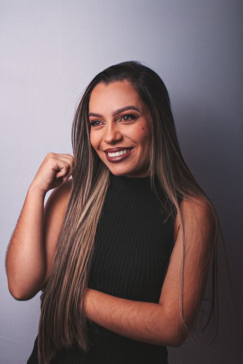 Free A joyful woman in a black dress smiles confidently against a neutral background. Stock Photo