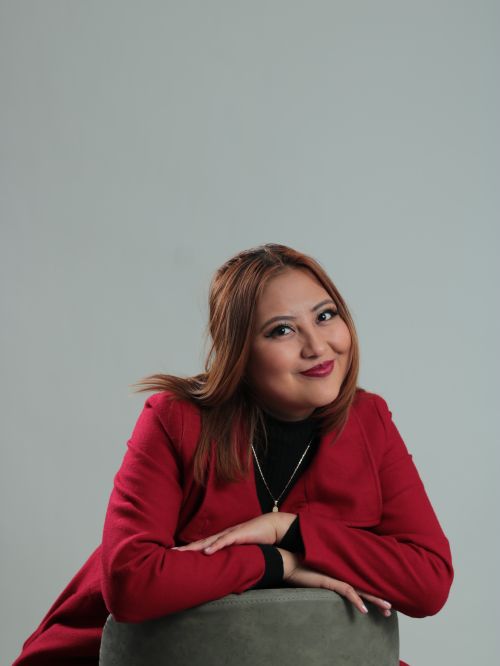 Free Confident woman in red coat with necklace smiling during a studio shoot. Stock Photo
