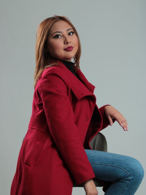 Free Fashion portrait of a woman in a red coat posing stylishly in a studio setting. Stock Photo