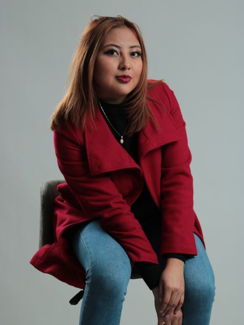 Free Fashion portrait of a woman in a red coat sitting on a stool against a white background. Stock Photo