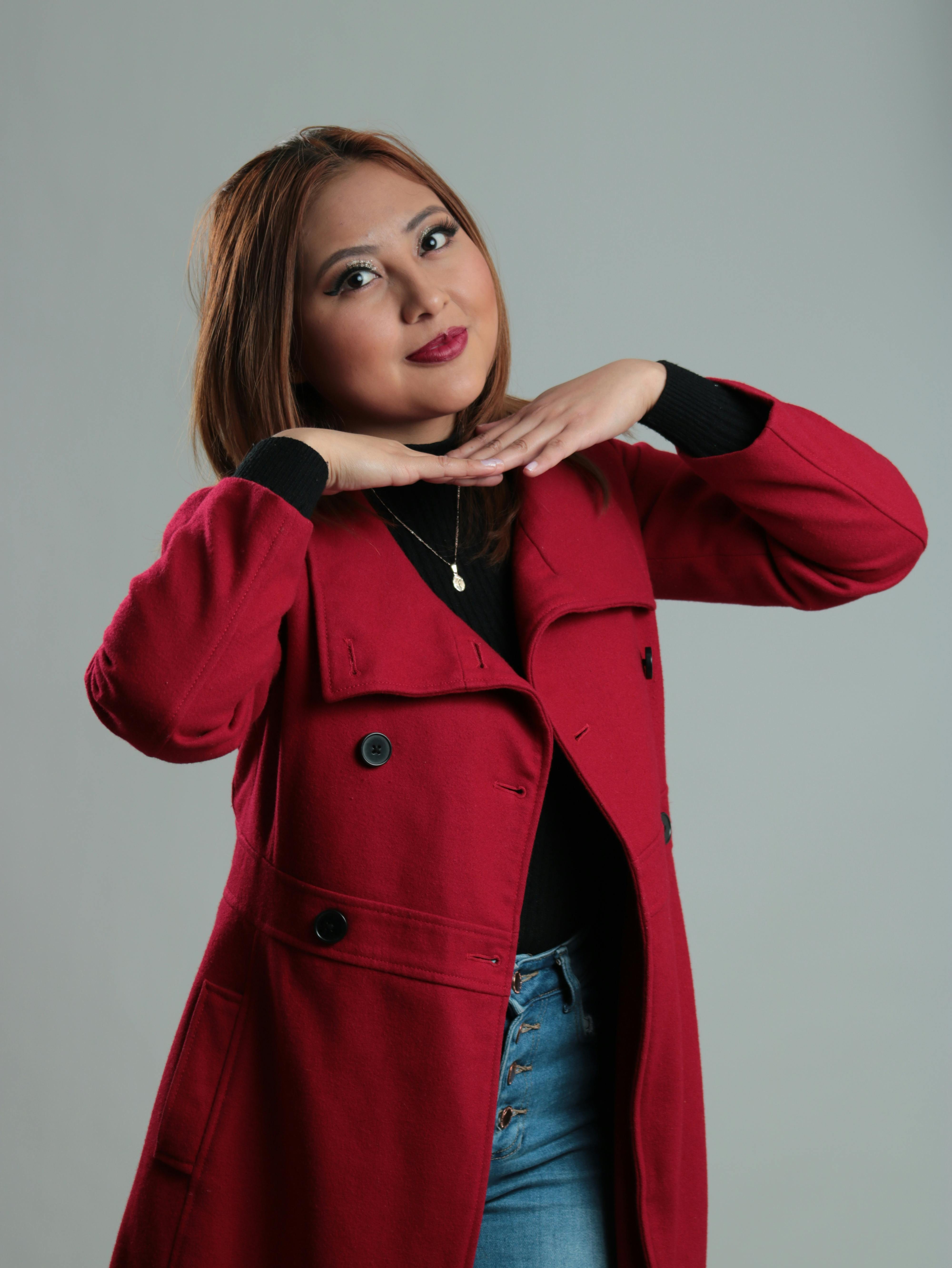 Studio portrait of a woman smiling with brown hair, wearing a red coat.