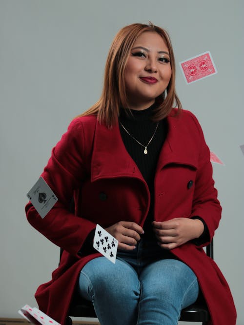 Cards Flying around Smiling Woman in Red Coat