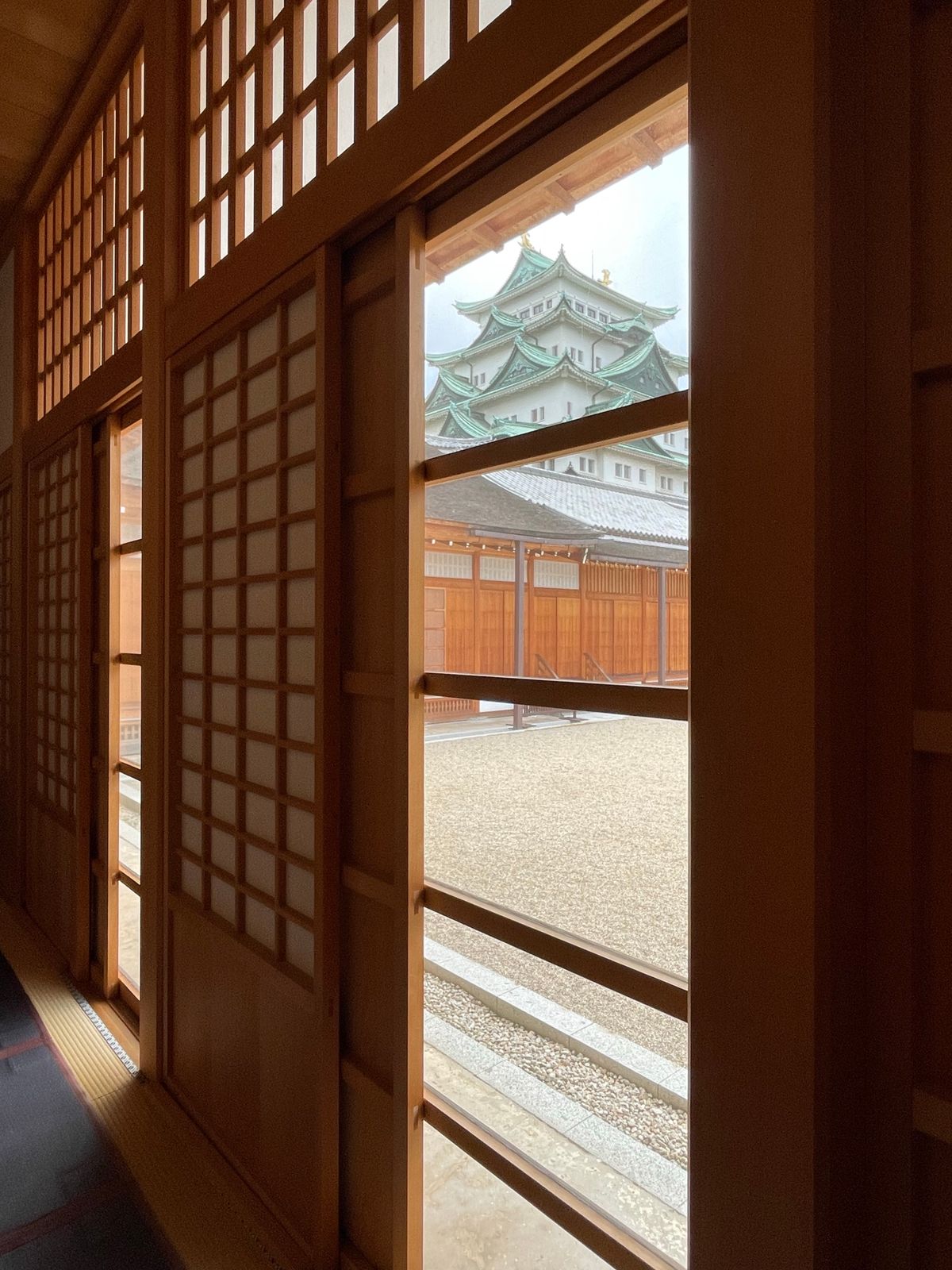 A view of Nagoya Castle framed by traditional wooden architecture