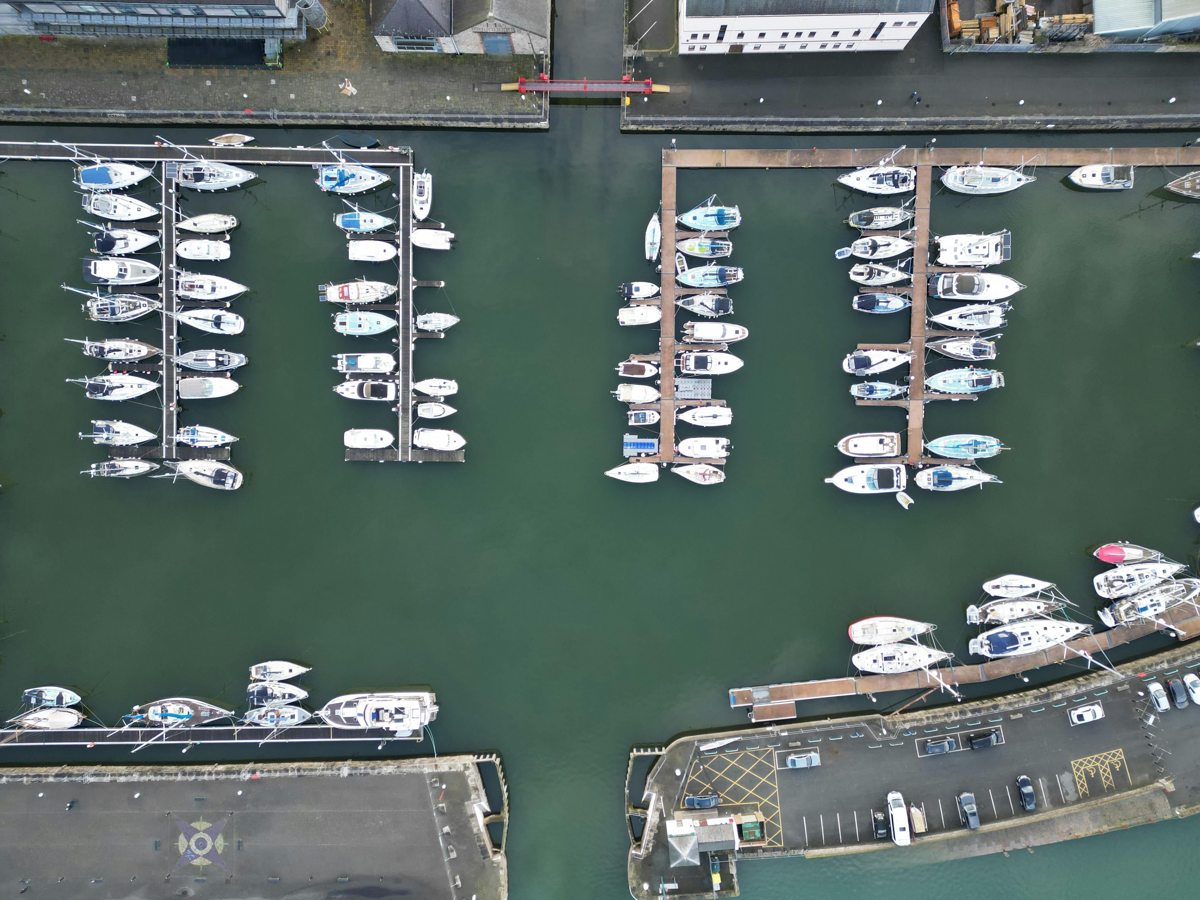 Drone shot of yachts moored at Caernarfon Marina, showcasing the docked vessels from above.