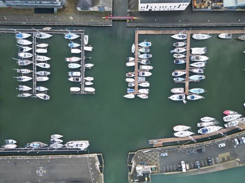 Free Drone shot of yachts moored at Caernarfon Marina, showcasing the docked vessels from above. Stock Photo