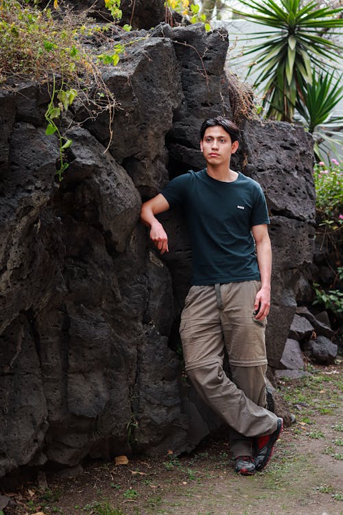 Brunette Man Standing by Rocks Wall