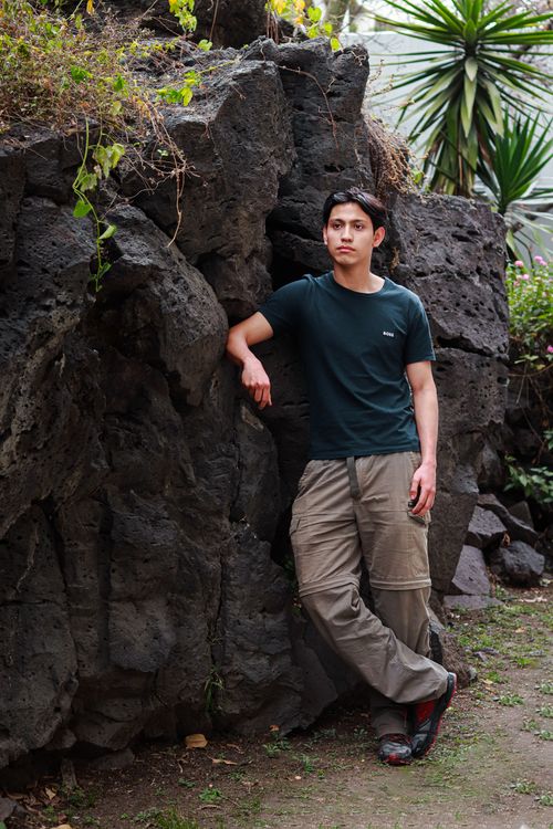Free Young man leaning casually against a rock wall in Ciudad de México. Stock Photo