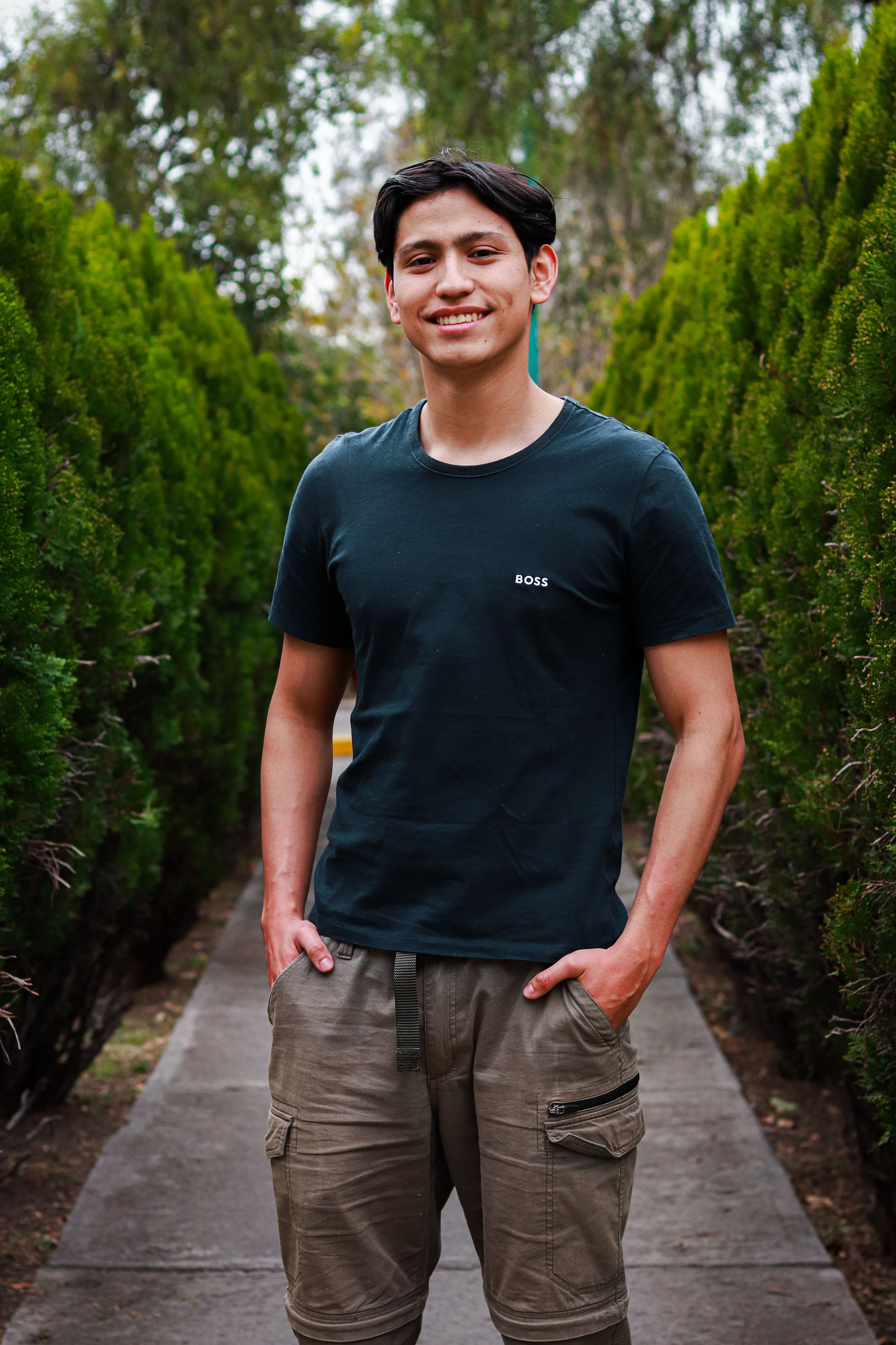 Young man in cargo pants and t-shirt smiling in a park in Ciudad de México, Mexico.