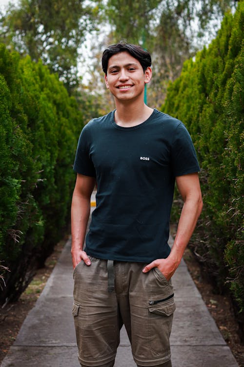A young man standing in a garden wearing a black shirt