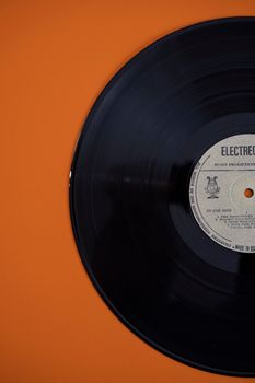 A classic vinyl record with label detail on an orange background, perfect for retro music themes.