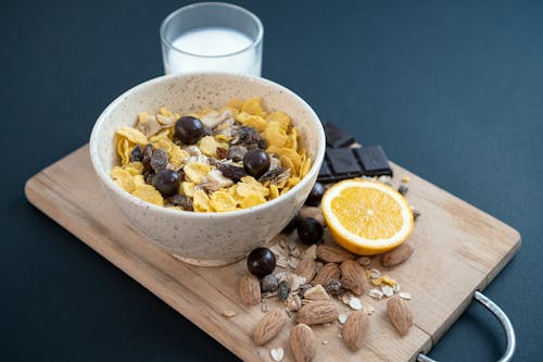 A bowl of cereal with almonds, chocolate and orange slices