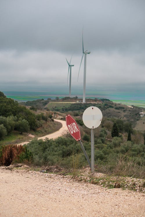 A stop sign on a dirt road next to a windmill