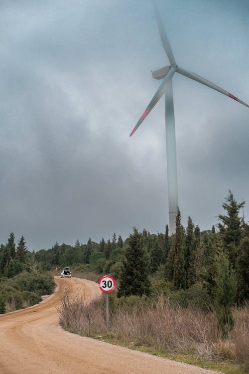 A wind turbine on a dirt road in the middle of a forest