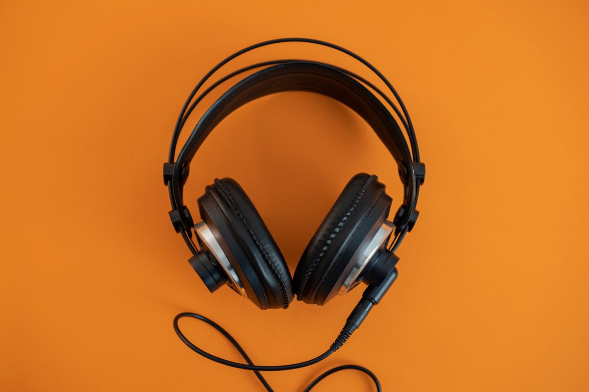 Black wireless headphones on an orange background
