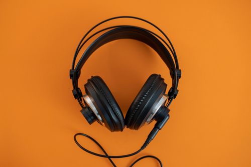 Free Top view of modern black headphones elegantly posed on a vibrant orange surface. Stock Photo
