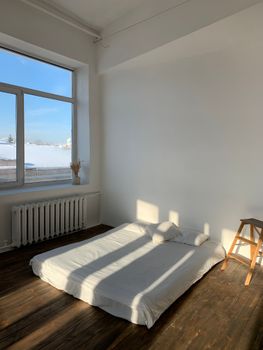 Bright minimalist bedroom with a floor mattress and sunlit ambiance, ideal for serenity.