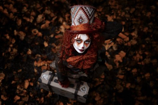 A woman in a vibrant costume and painted face poses on fallen leaves, capturing the essence of fall and Halloween.