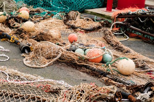 Free Tangled fishing nets and buoys lie on the ground, showcasing fishing gear details. Stock Photo