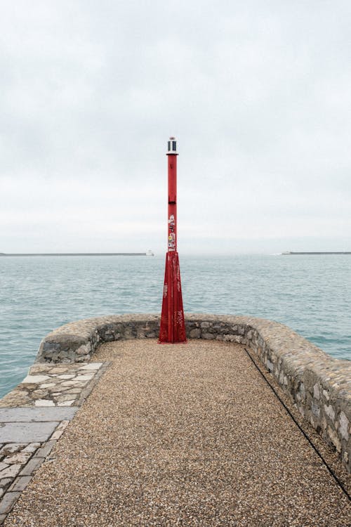 A red light pole on a pier by the water