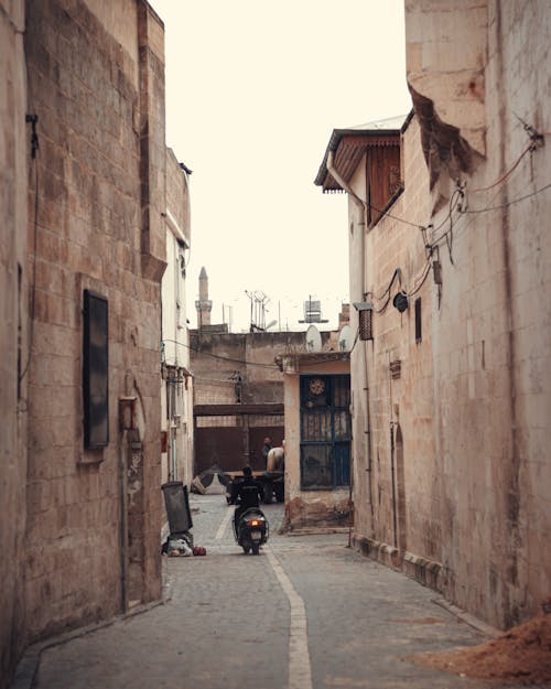 A man on a motorcycle rides down a narrow alley