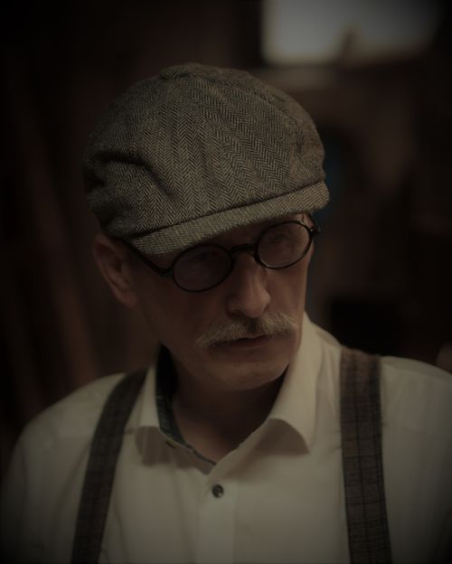 Free Portrait of a man in vintage attire with glasses and ivy cap in warm tones. Stock Photo