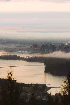 Stunning twilight aerial view of Vancouver skyline, showcasing iconic Lions Gate Bridge and cityscape over Fraser River.