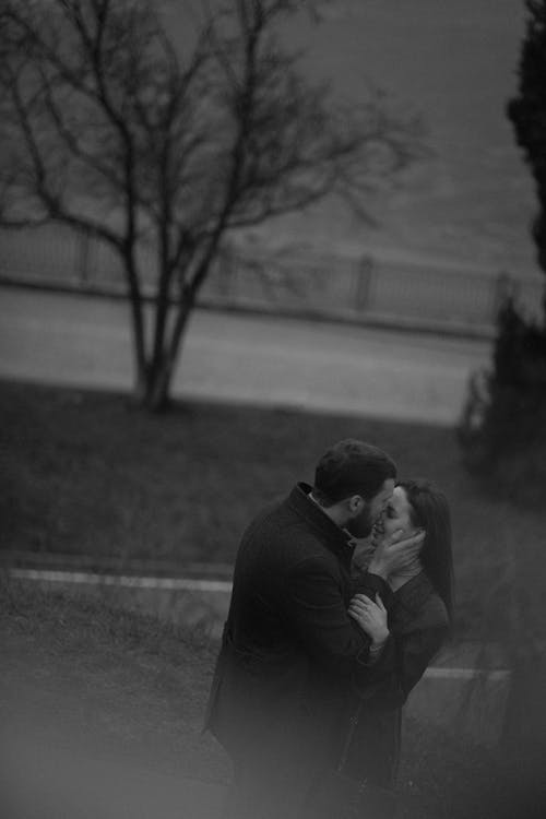 A couple kissing in black and white on a hill