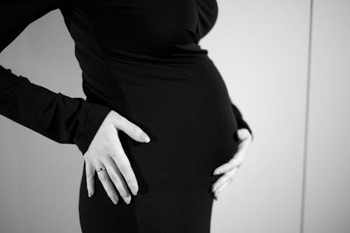 A pregnant woman in black and white holding her belly