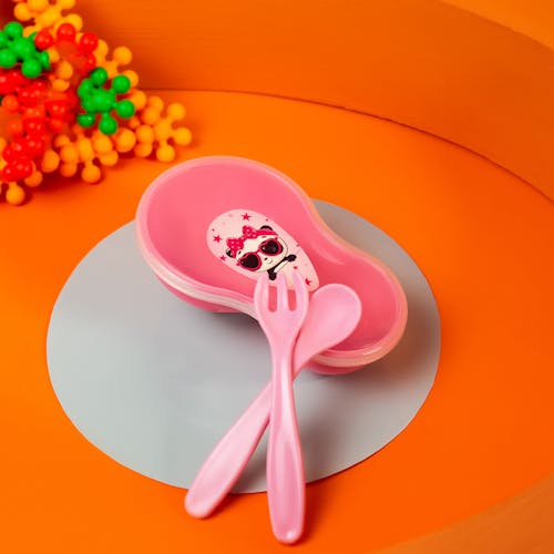 A pink plastic bowl with a spoon and fork