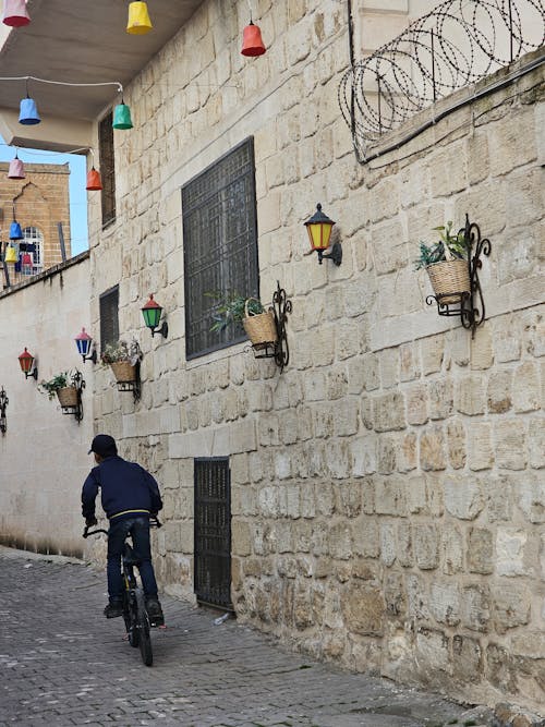 Boy Riding Bike near Stone Building Wall