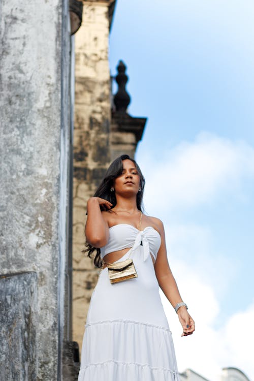 A woman in a white dress and gold clutch