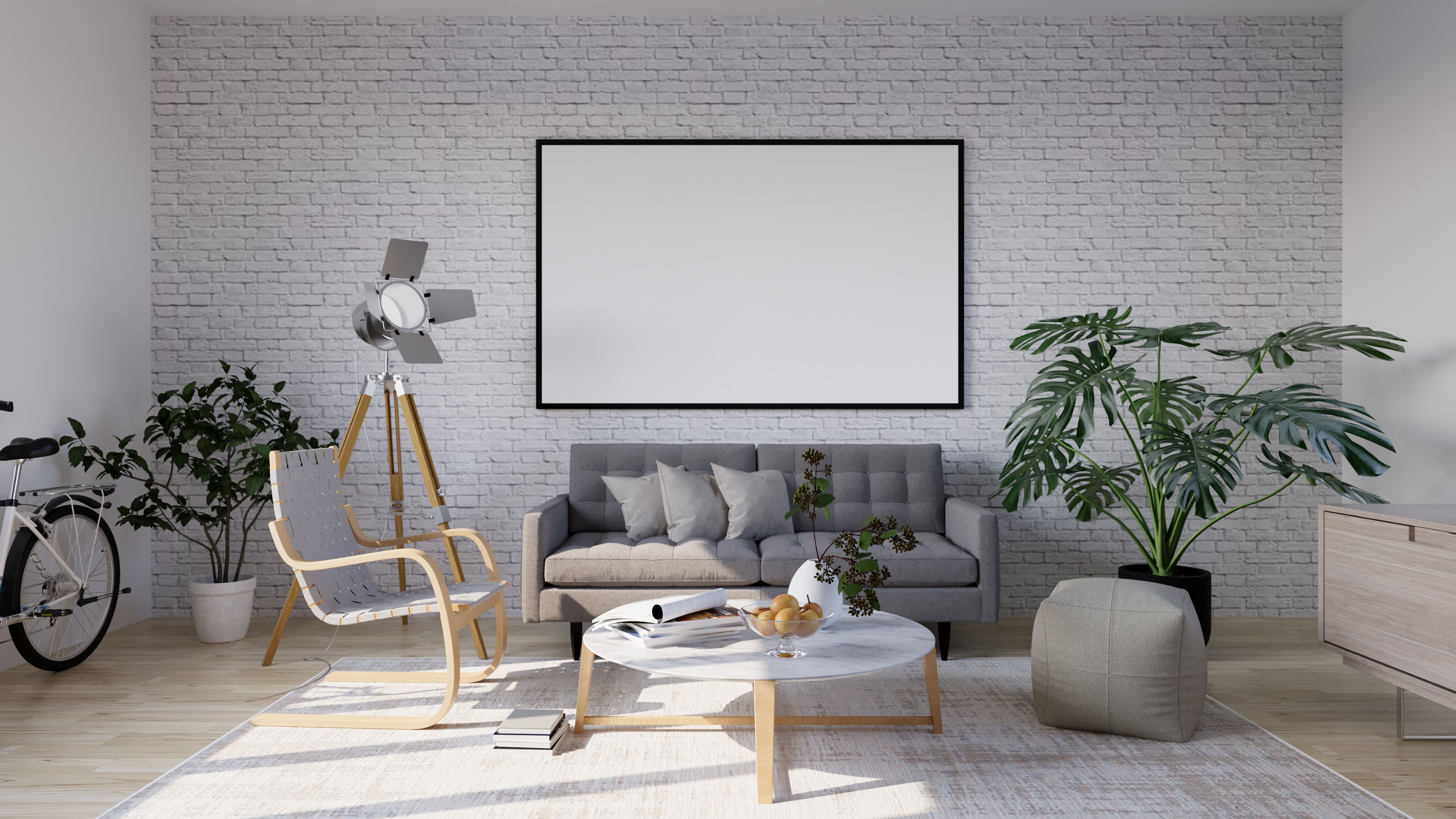 Minimalist living room with framed blank wall art hung above gray sofa against white brick wall