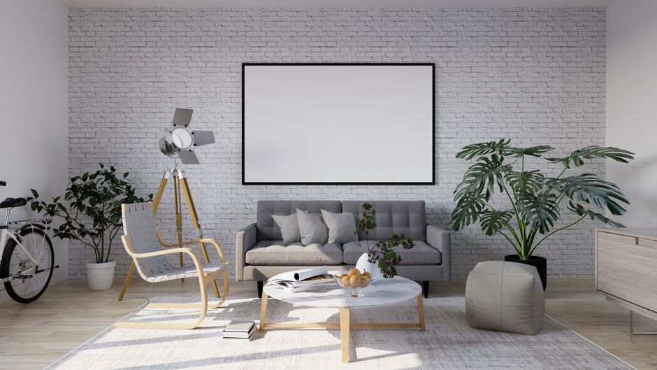 Minimalist living room with framed blank wall art hung above gray sofa against white brick wall