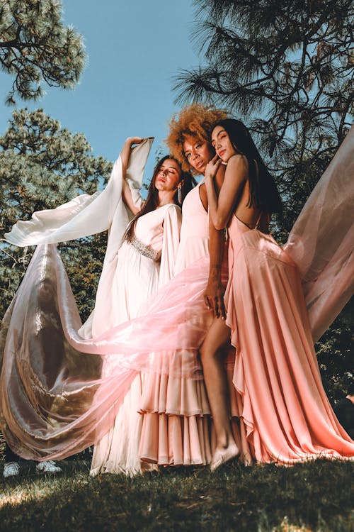 Three women in long dresses pose for a photo