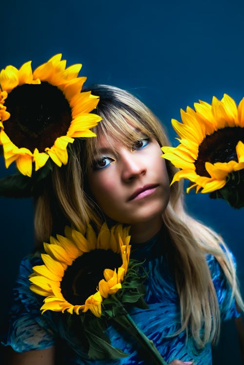 A woman with long blonde hair holding sunflowers
