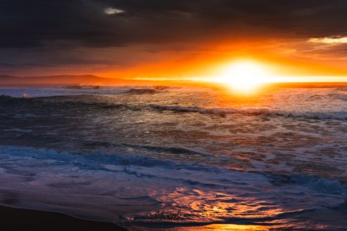 Free A vivid sunset over the ocean with dramatic storm clouds, creating a breathtaking seascape. Stock Photo