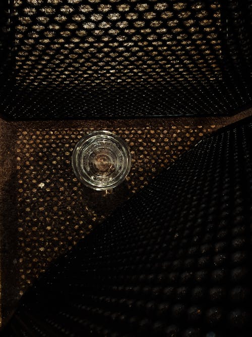 A glass of water sitting on top of a metal grate