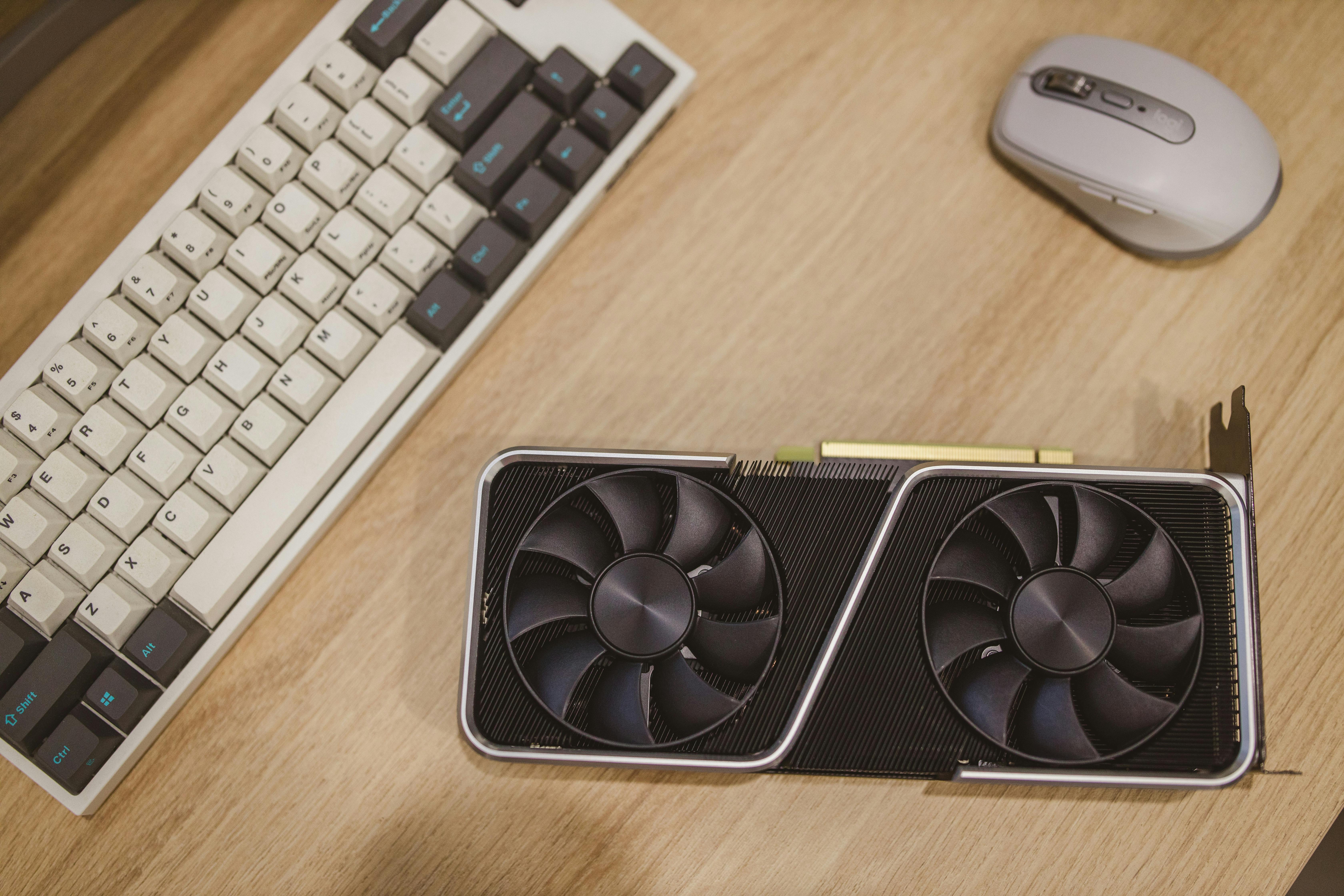A Computer Graphics Card Lying on a Desk next to a Keyboard and a Mouse ...