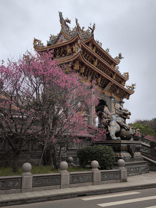 A chinese pagoda with pink flowers in front of it
