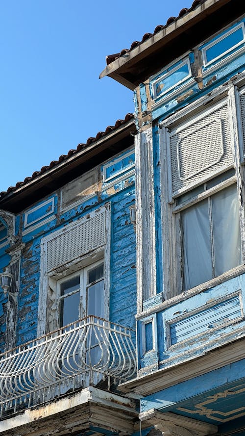 A blue and white house with a balcony and balcony railing