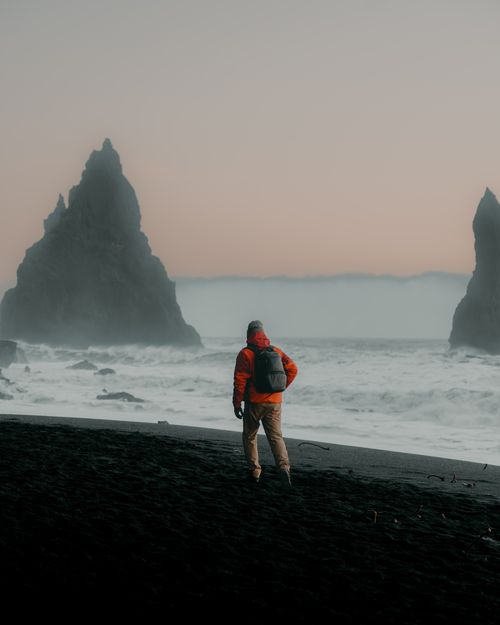 Free A solitary figure with a backpack explores the foggy coastline, surrounded by rugged sea stacks. Stock Photo