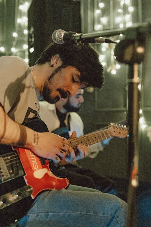 A man playing guitar in front of a microphone