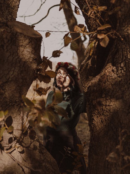 A woman is standing in the woods with leaves on her face